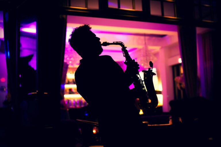 Silhueta de saxofonista tocando em ambiente com luzes roxas e rosas, clima intenso e noturno