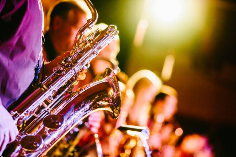 Fileira de saxofonistas em um palco com luzes quentes desfocadas ao fundo