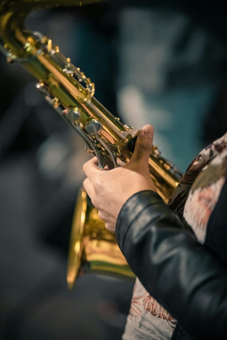 Close-up dourado das chaves de um saxofone sendo segurado por um músico, tons quentes