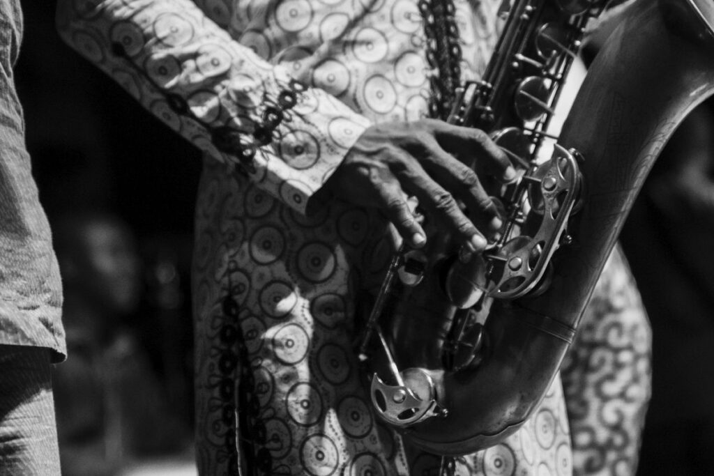 Fotografia em preto e branco de um saxofonista concentrado manuseando as chaves do instrumento